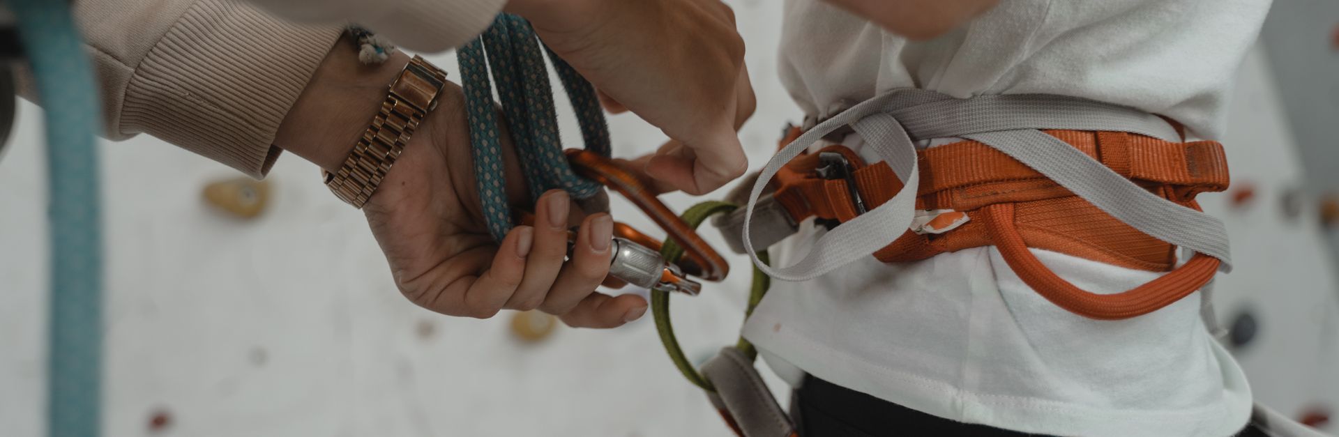 Detailed view of a rock climber preparing with harness and ropes. Indoor climbing setup.
