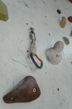 Detailed view of carabiners attached to climbing holds on an indoor rock climbing wall.