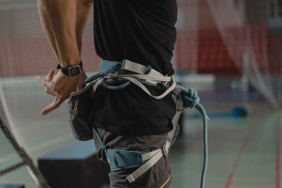 아이폰17 |모델·용량 선택 가이드 13 Man preparing for indoor rock climbing, adjusting harness and rope gear.