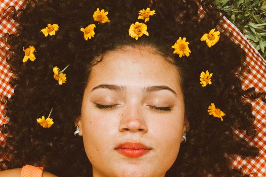 一位闭着眼睛、卷发、戴着花朵的女人的特写肖像
