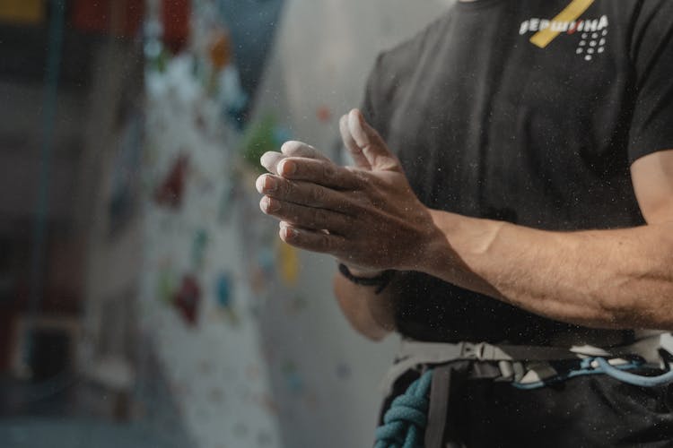 A Person Wearing A Black Shirt Dusting Chalk From Hands