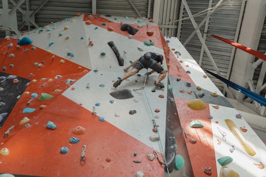 A climber scales a colorful indoor rock wall, showcasing agility and strength.