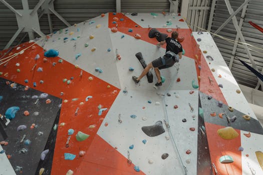 Man climbing colorful indoor wall with determination and skill in a gym setting.
