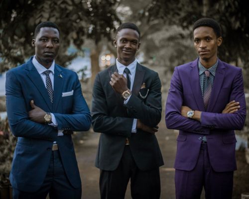 Free Three young men in elegant suits posing confidently outdoors. Stock Photo