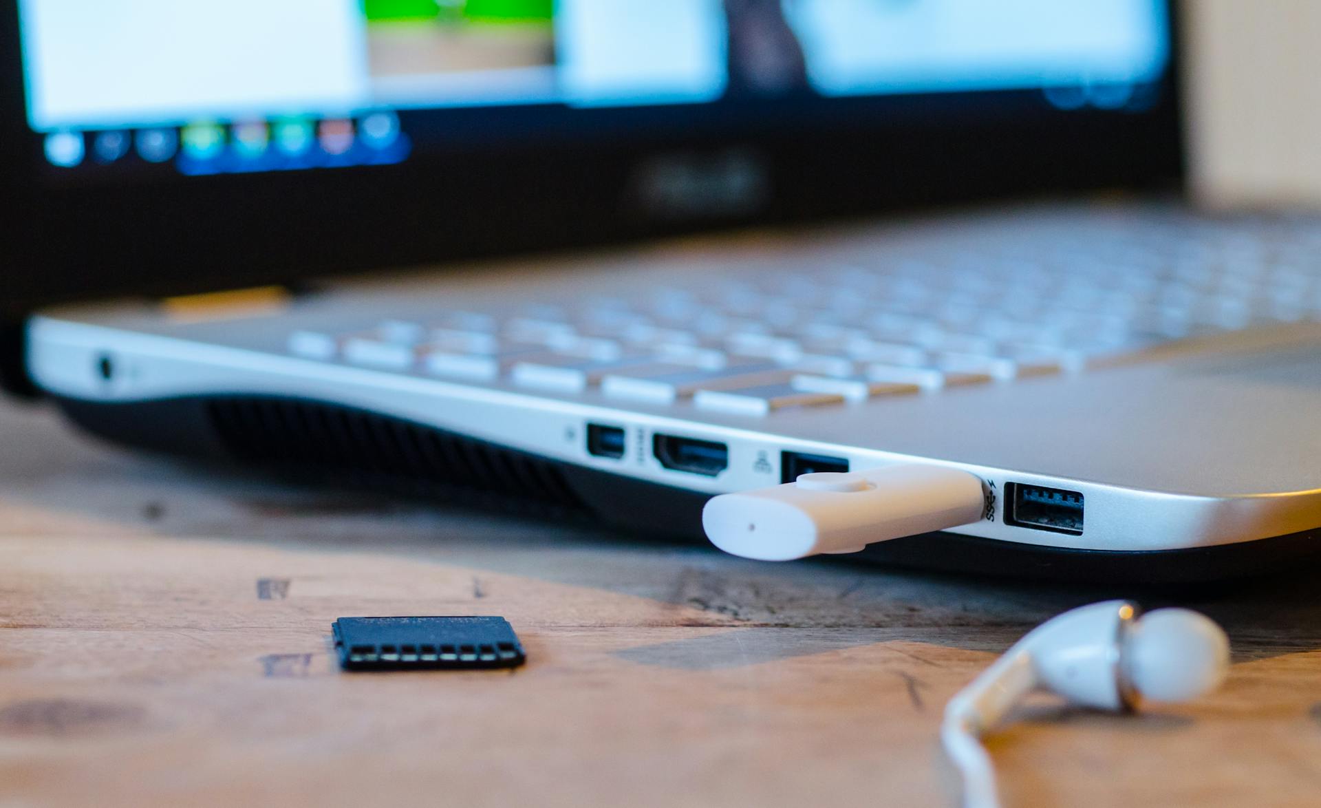 Close-up image of a laptop with USB device connected and earphones lying nearby.