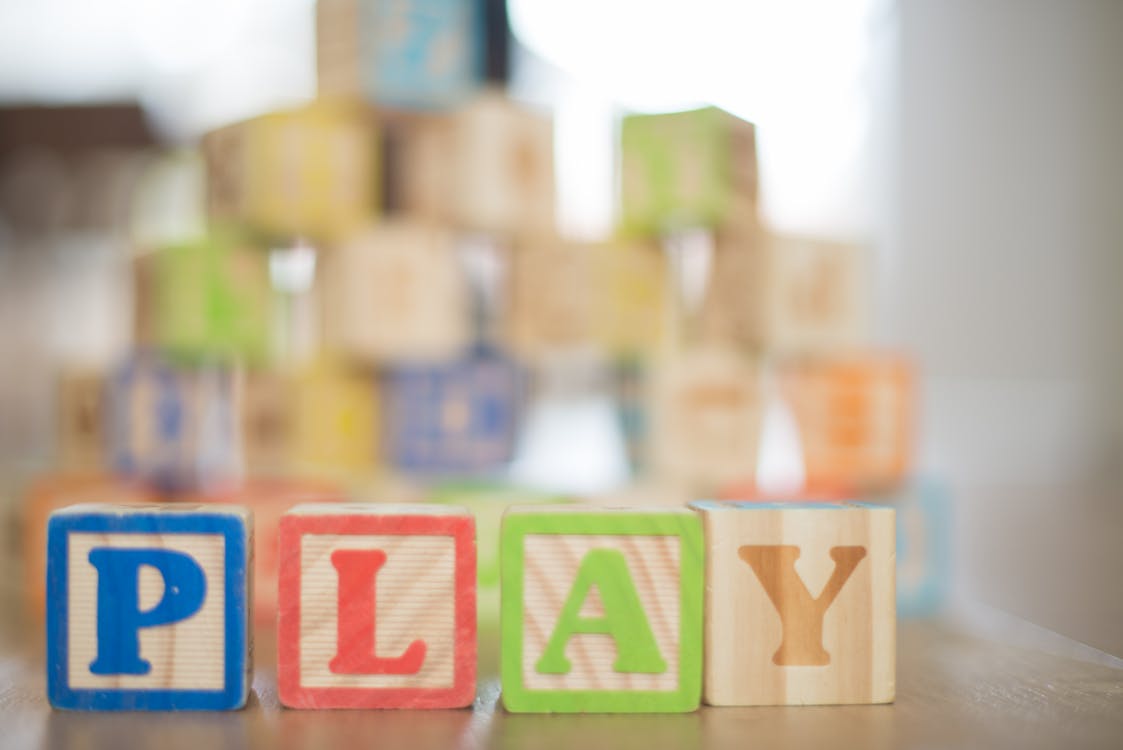 Depth of Field Photography of P, L, A, Y Wooden Letter Decors on Top of Beige Wooden Surface