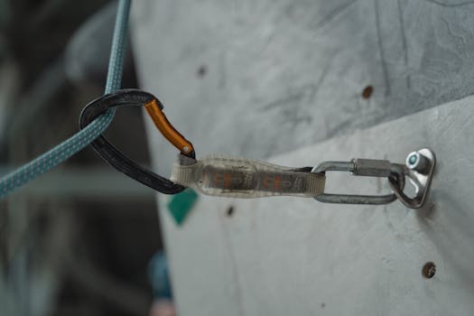 Detailed close-up of climbing gear and carabiner attached to a climbing wall, showcasing outdoor adventure equipment.