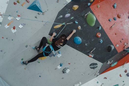 A determined woman climbing a vibrant indoor climbing wall, showcasing strength and athleticism.