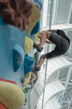 A man scaling a vibrant indoor climbing wall with determination and agility.