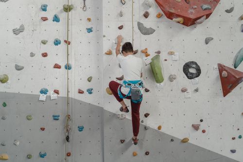 Free A man engaged in rock climbing on an indoor climbing wall, showcasing fitness and strength. Stock Photo