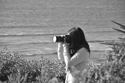 Grayscale Photograph of a Woman Using Dslr Camera