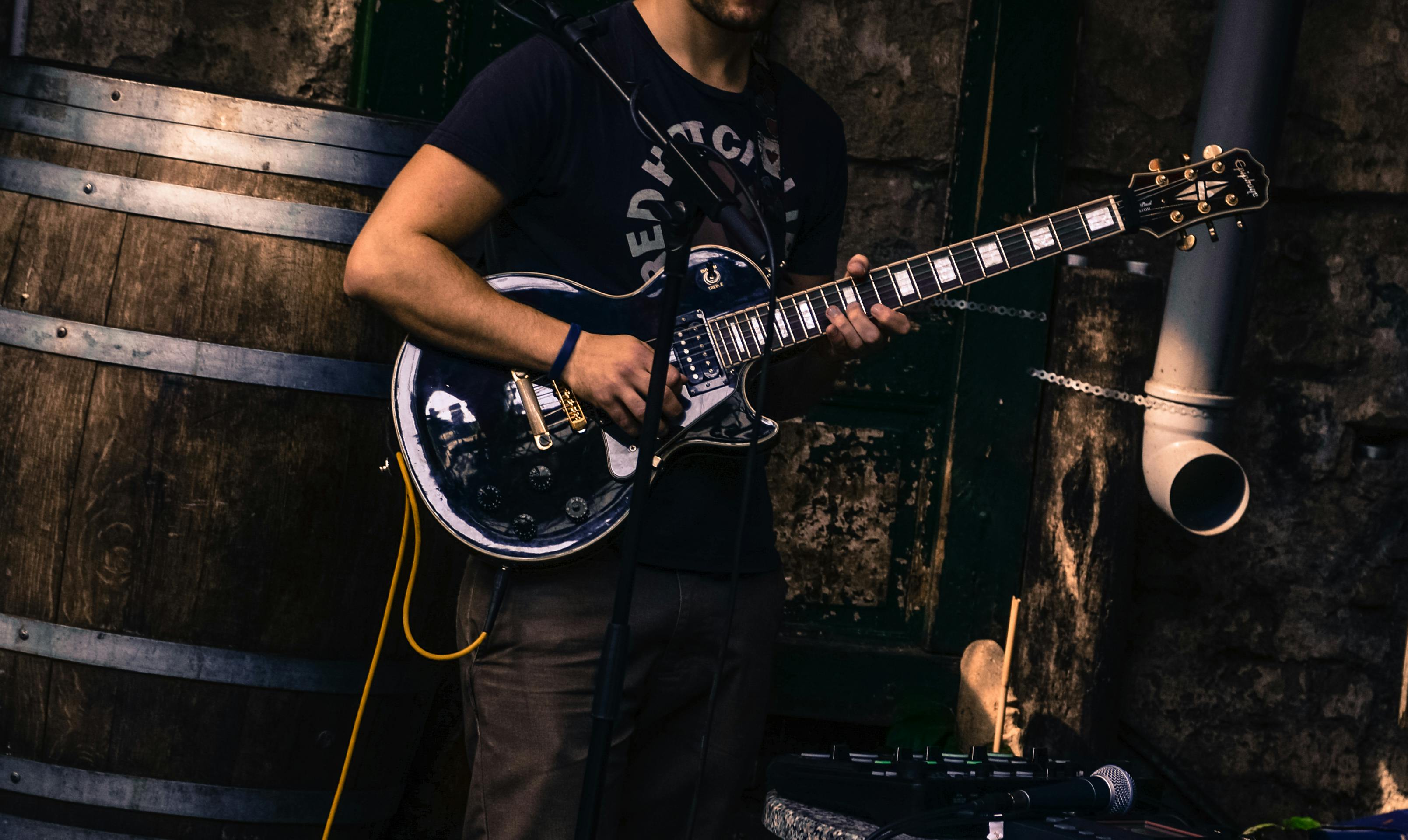 man-sitting-on-guitar-amplifier-playing-electric-guitar-free-stock-photo