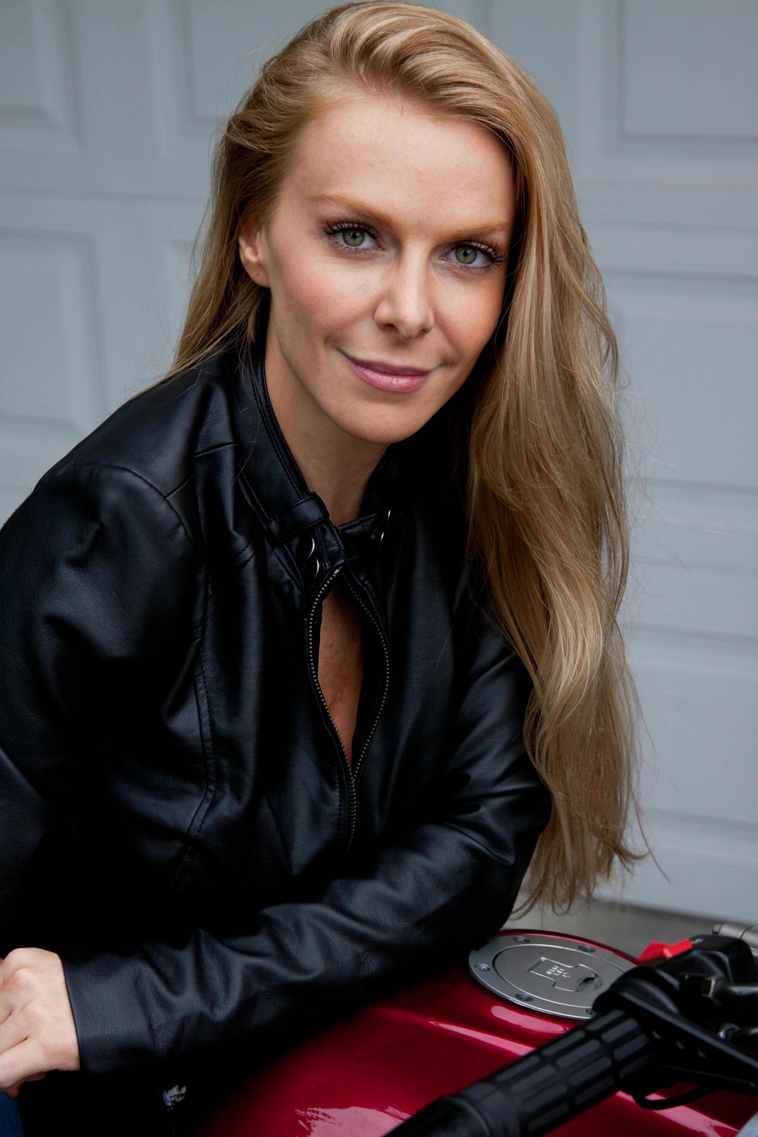 Smiling woman in a black leather jacket posing confidently.