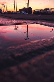Reflection of power lines and sky in a puddle at sunset. Urban landscape captured beautifully.
