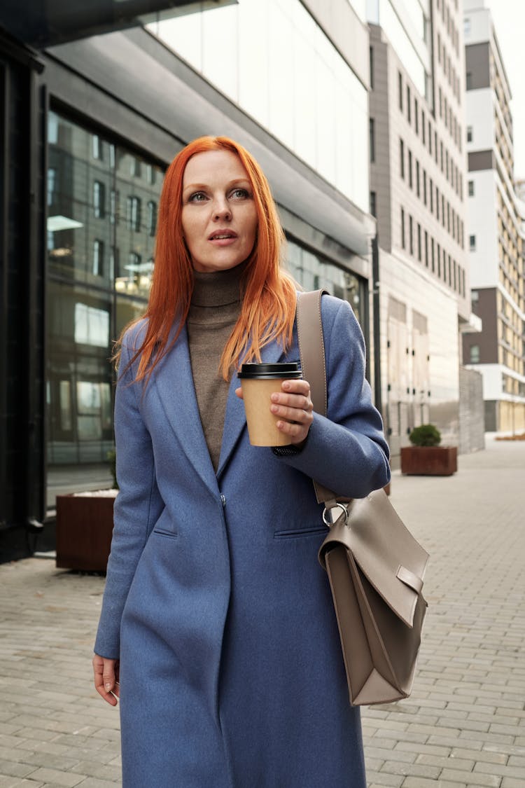 A Woman Walking While Holding A Cup Of Coffee