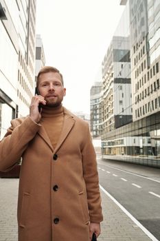 在城市环境中，一位穿着棕色外套的自信商人正在打电话