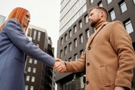 Man in Brown Coat Holding Man in Blue Long Sleeve Shirt