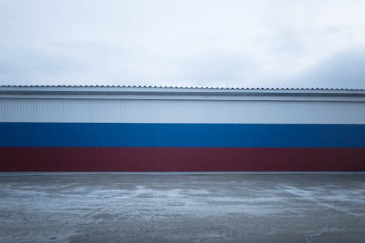 Horizontal shot of a tricolor industrial building facade against a cloudy sky.