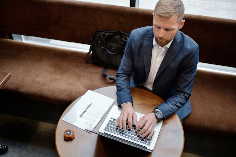 A Man In A Suit Typing On Laptop