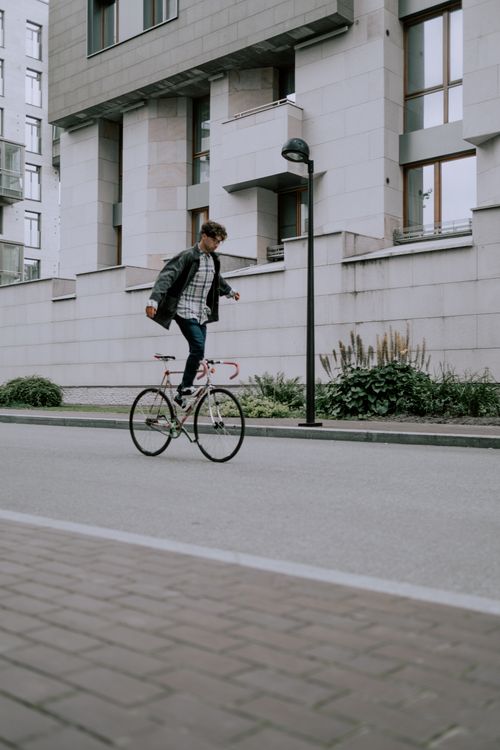 Free A man skillfully balances on a bicycle in an urban cityscape, showcasing an impressive stunt. Stock Photo