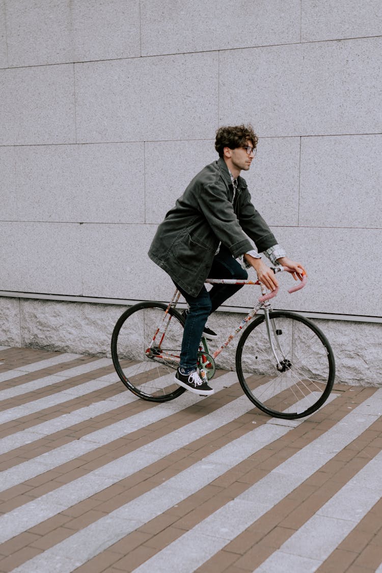 A Man In Green Coat Riding A Bicycle