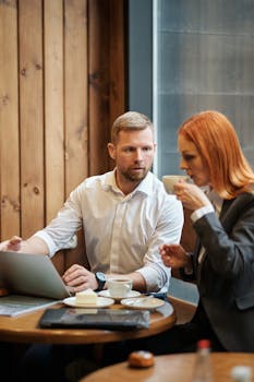 Professional man and woman discussing work over coffee in a trendy café.