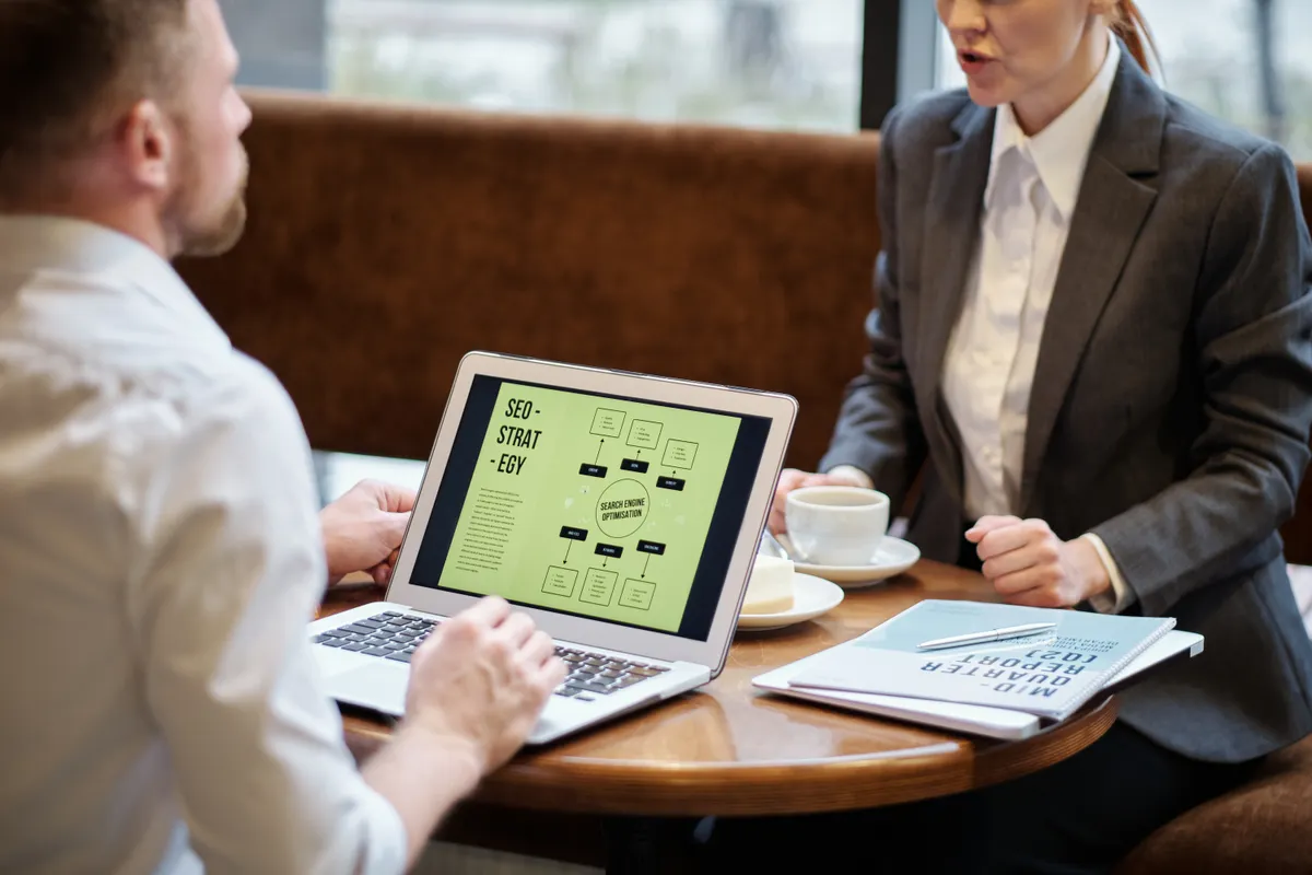 Two colleagues reviewing a website SEO optimization strategy on a laptop.