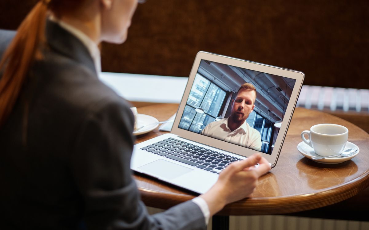 A businesswoman in a cafe using a laptop for an online video conference call.