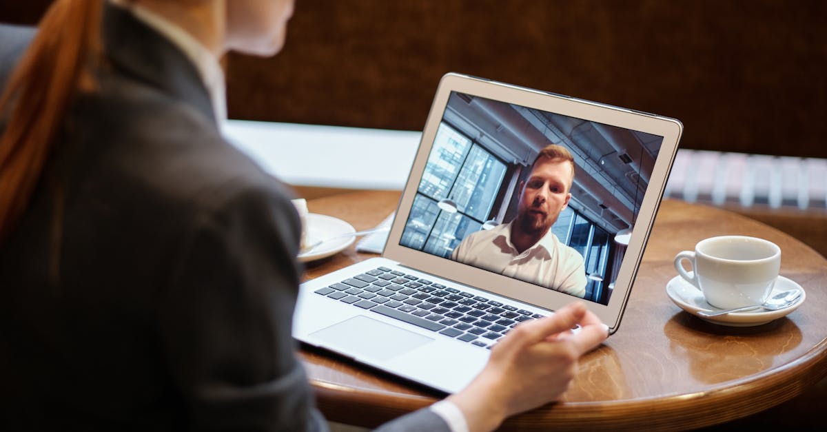 A businesswoman in a cafe using a laptop for an online video conference call.