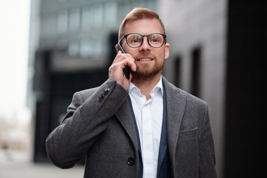 一名穿着灰色外套的职业男子正在城市环境中打电话
