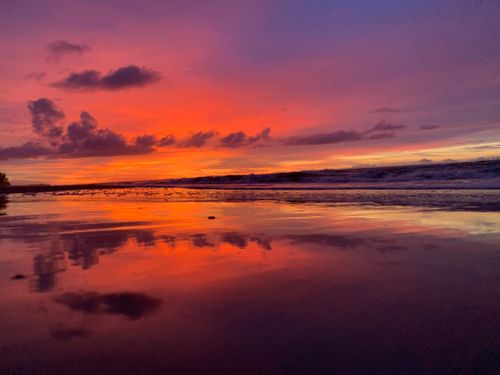 Free Stunning beach sunset with vivid colors reflecting on the ocean, capturing tranquil natural beauty. Stock Photo