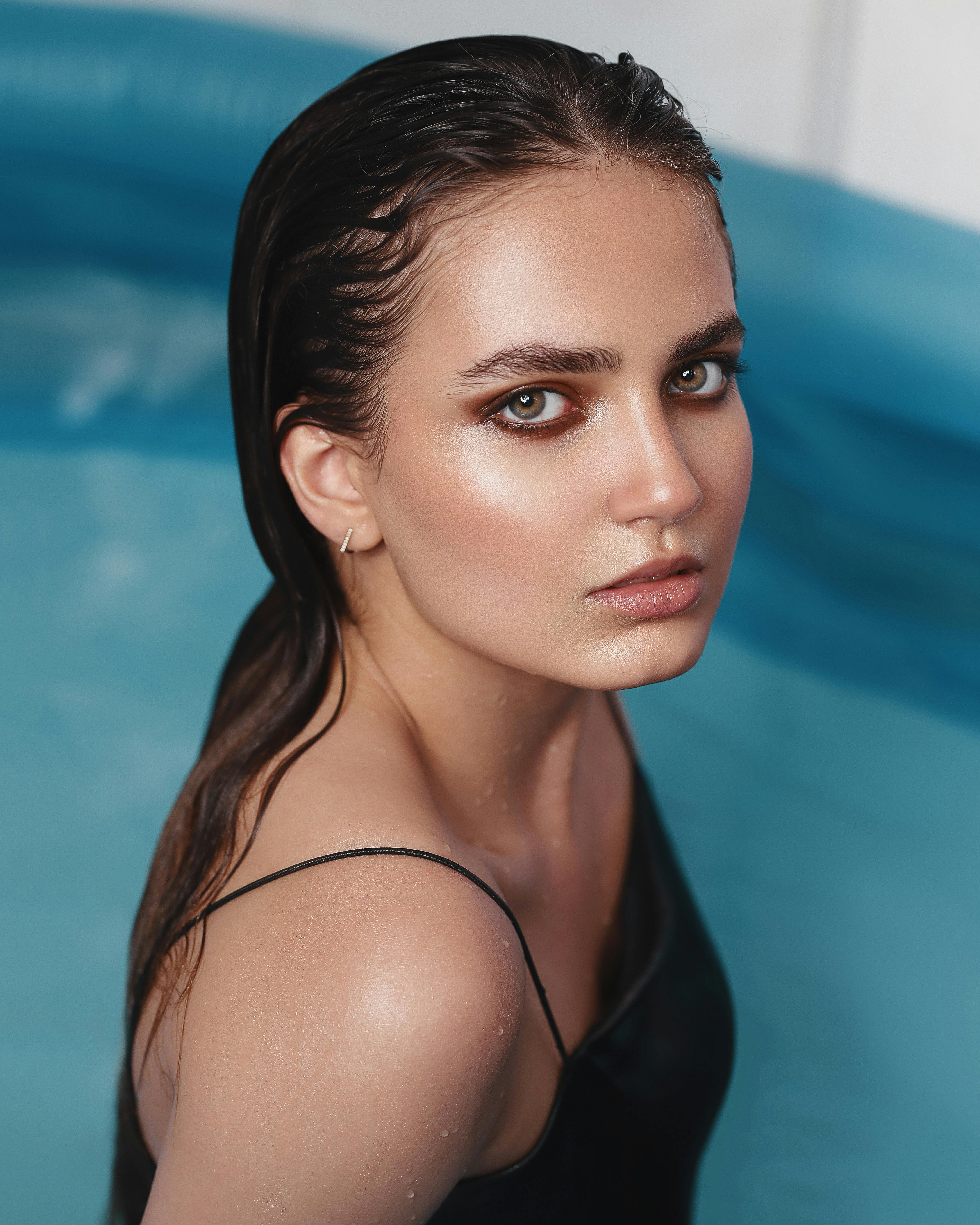 Stylish portrait of a woman with wet hair in a pool, exuding elegance and sophistication.