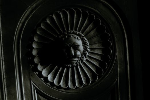 Creative plaster moulding in shape on lion head on facade of aged building