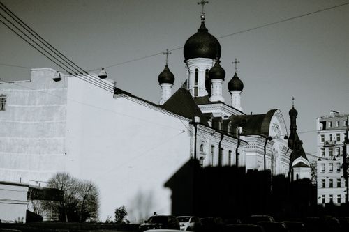 Free Black and white of old Orthodox church facade with cupolas and crosses against multistory house in city Stock Photo