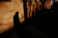 Anonymous citizen shade on house wall on dark city street