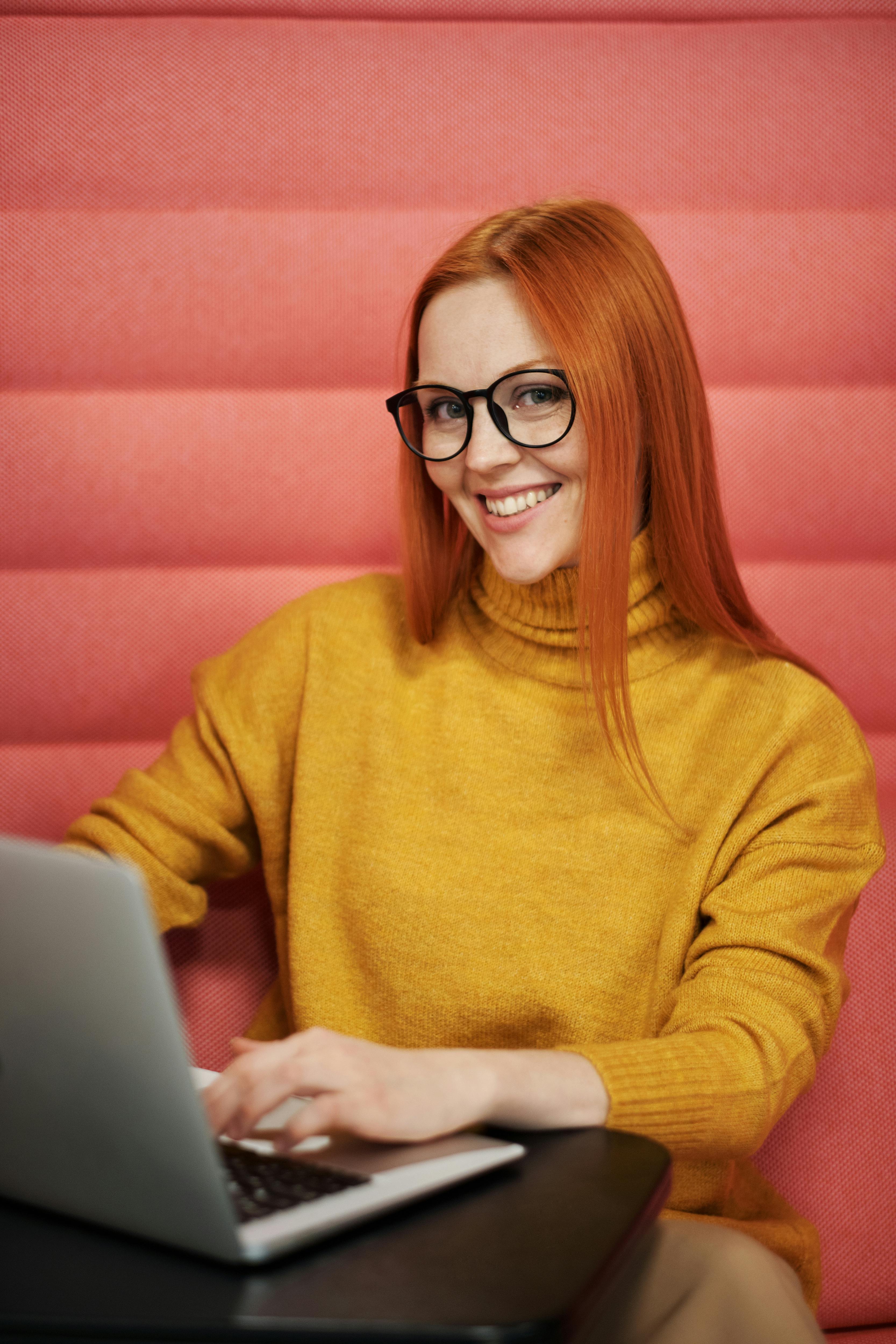 a smiling woman wearing a yellow sweater and eyeglasses