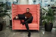 Woman in Black Pants Sitting on Red Sofa Chair