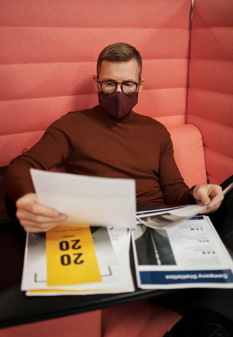 A Businessman Wearing Face Mask Reading Documents