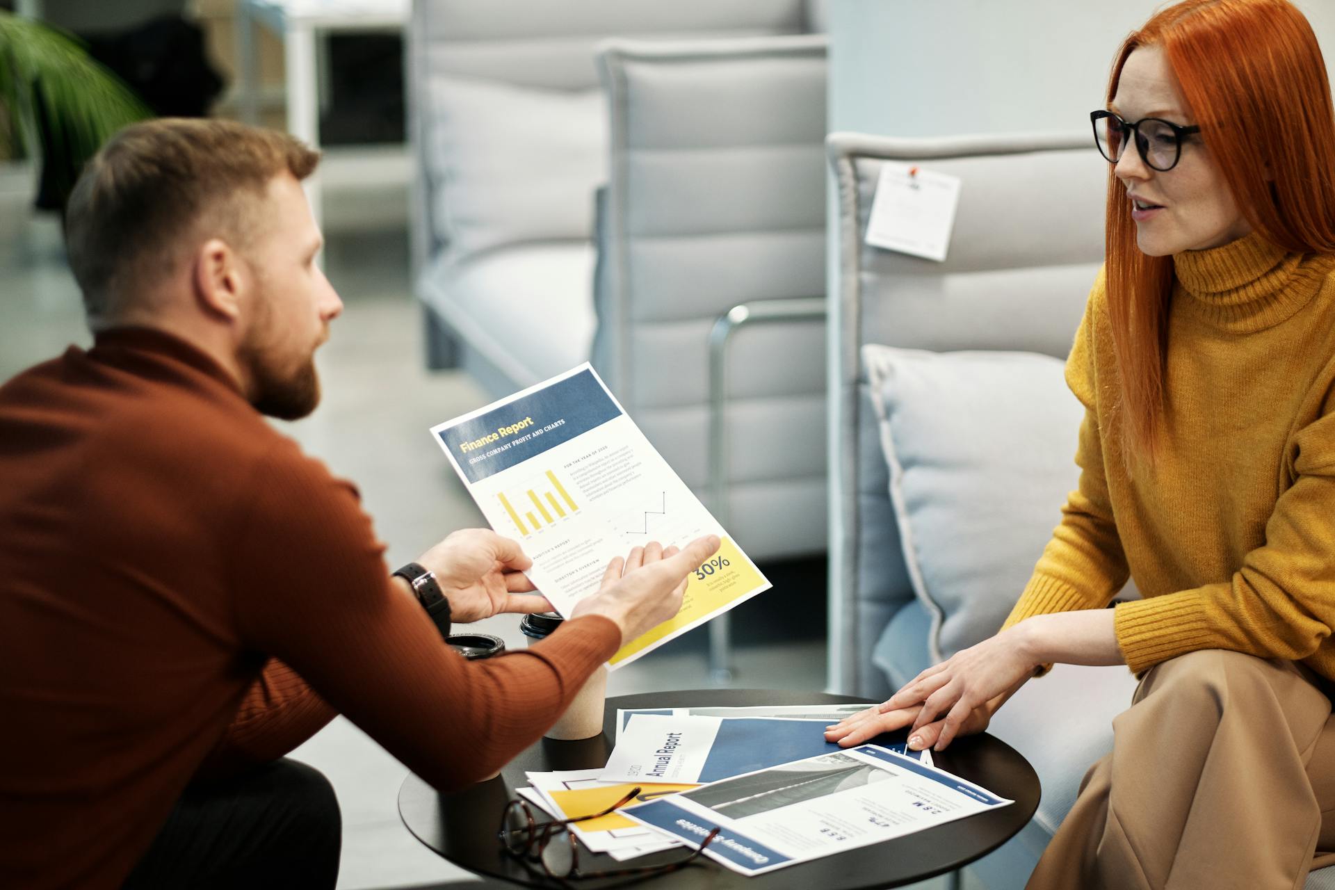 Colleagues discussing financial documents during an office meeting. Professional teamwork setup.