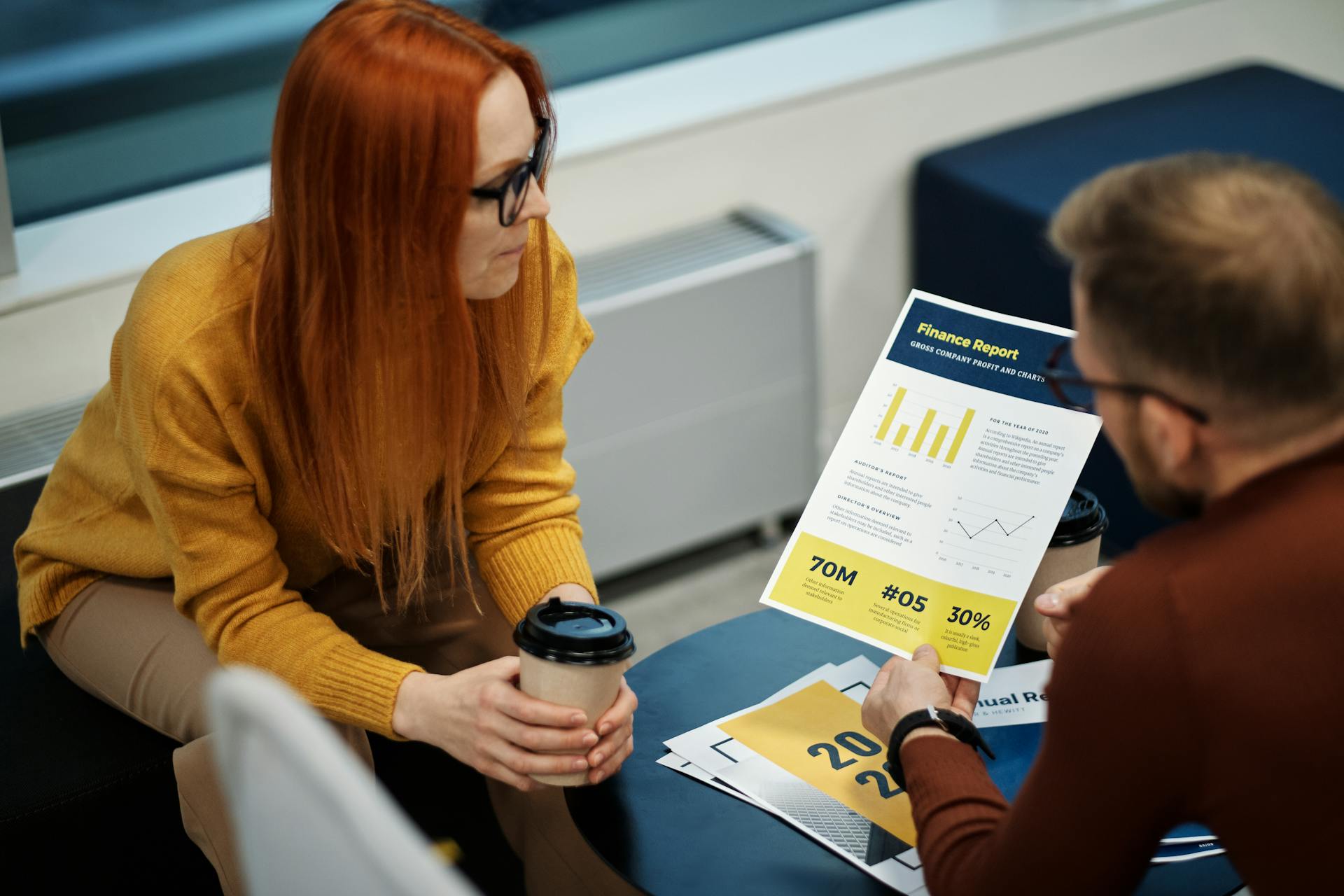 Two colleagues reviewing a financial report in a modern office setting.