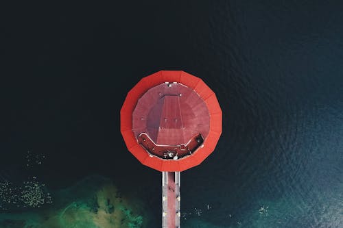 Aerial view of round red roof of modern restaurant located in river water in Dnipro city