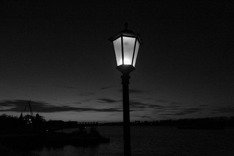 Dim Streetlight On Pier Of Calm River