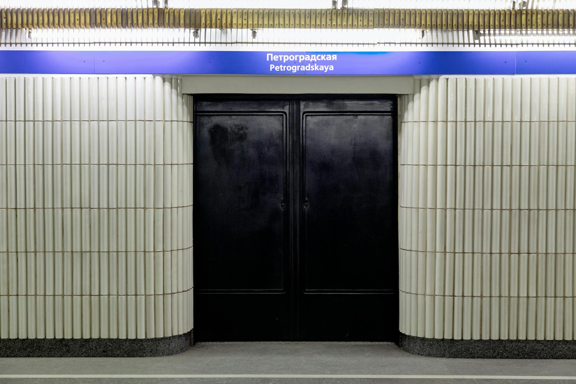 Entrance to Petrogradskaya Metro Station with ribbed white walls and black doors.