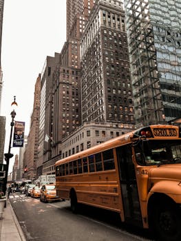 Urban street scene in NYC featuring a school bus amid towering skyscrapers.