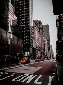 Dynamic city street view with iconic yellow taxis and towering skyscrapers in NYC.