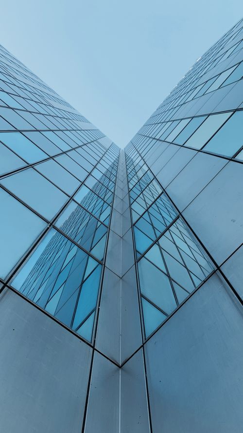 Free Low angle view of a modern glass office building in Amsterdam showcasing architectural geometry and reflections. Stock Photo