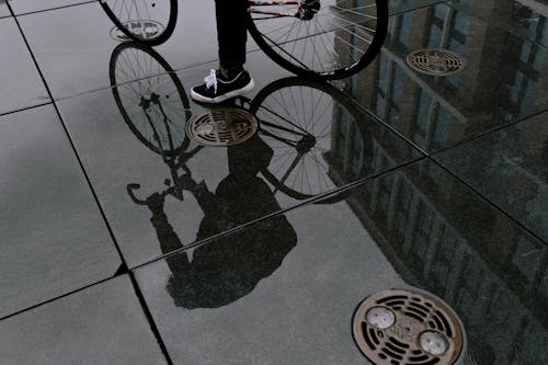 站在黑色和白色自行車上的黑褲子的人
