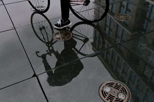 自行车和人在潮湿城市表面的艺术倒影，展现了现代城市生活