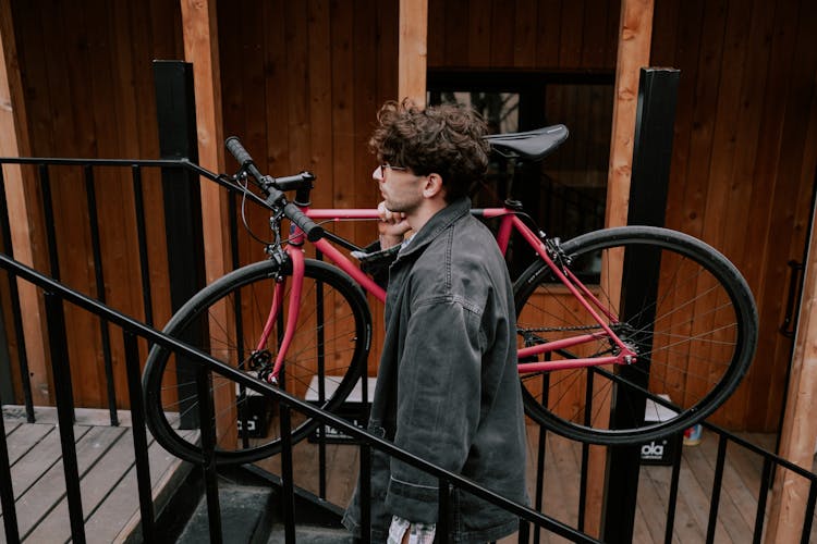 A Man Carrying A Bicycle While Going Up The Stairs