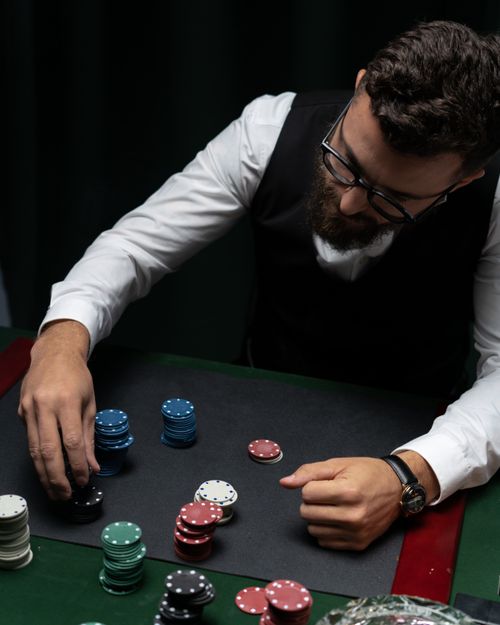 Free Bearded man in vest stacking poker chips at a casino table from above, focused and strategic. Stock Photo
